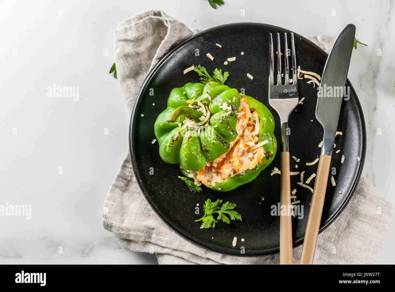 Herbst Rezepte. Hausgemachte gefüllte Paprika mit Hackfleisch, Karotten, Tomaten, Kräuter, Käse. Auf weissem Marmortisch, portioniert in Platte, mit Messer Stockfoto