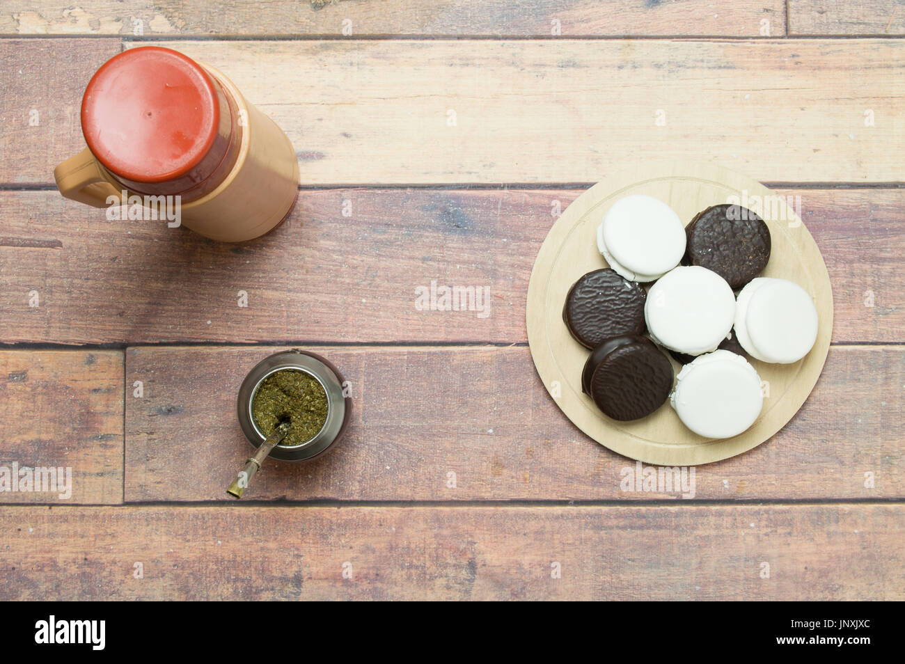 Draufsicht von Mate, Thermoskannen und Alfajores auf Holztisch Stockfoto