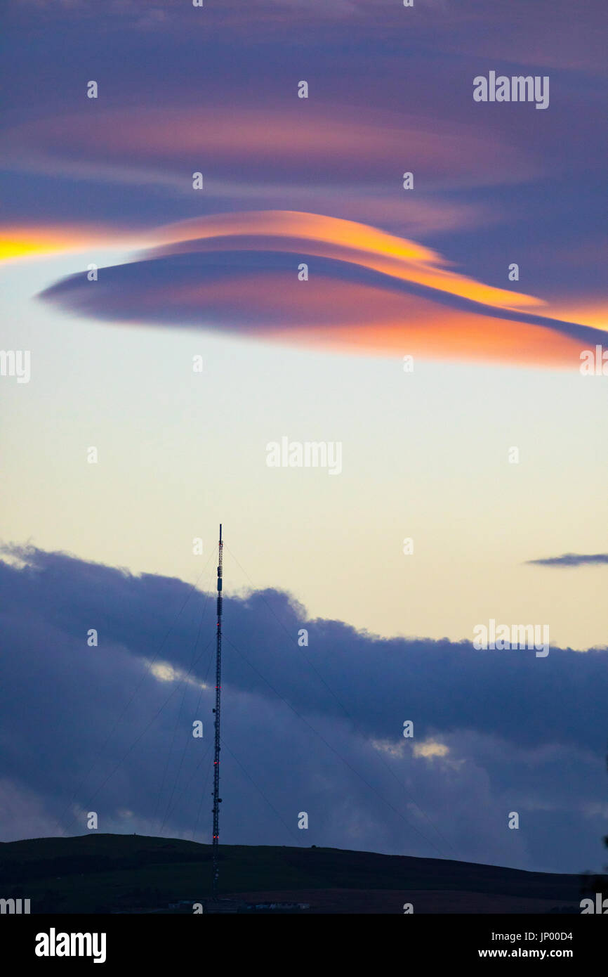 Seltsame Wolken bekannt als linsenförmige Wolken erscheinen über den Moel-y-Parc Mast auf den Hügeln Clwydian Range, Wales Stockfoto