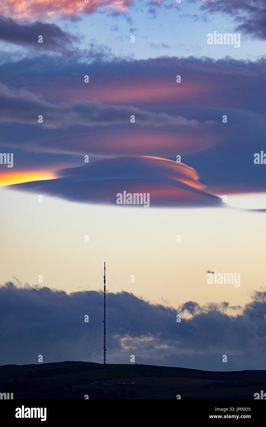 Seltsame Wolken bekannt als linsenförmige Wolken erscheinen über den Moel-y-Parc Mast auf den Hügeln Clwydian Range, Wales Stockfoto