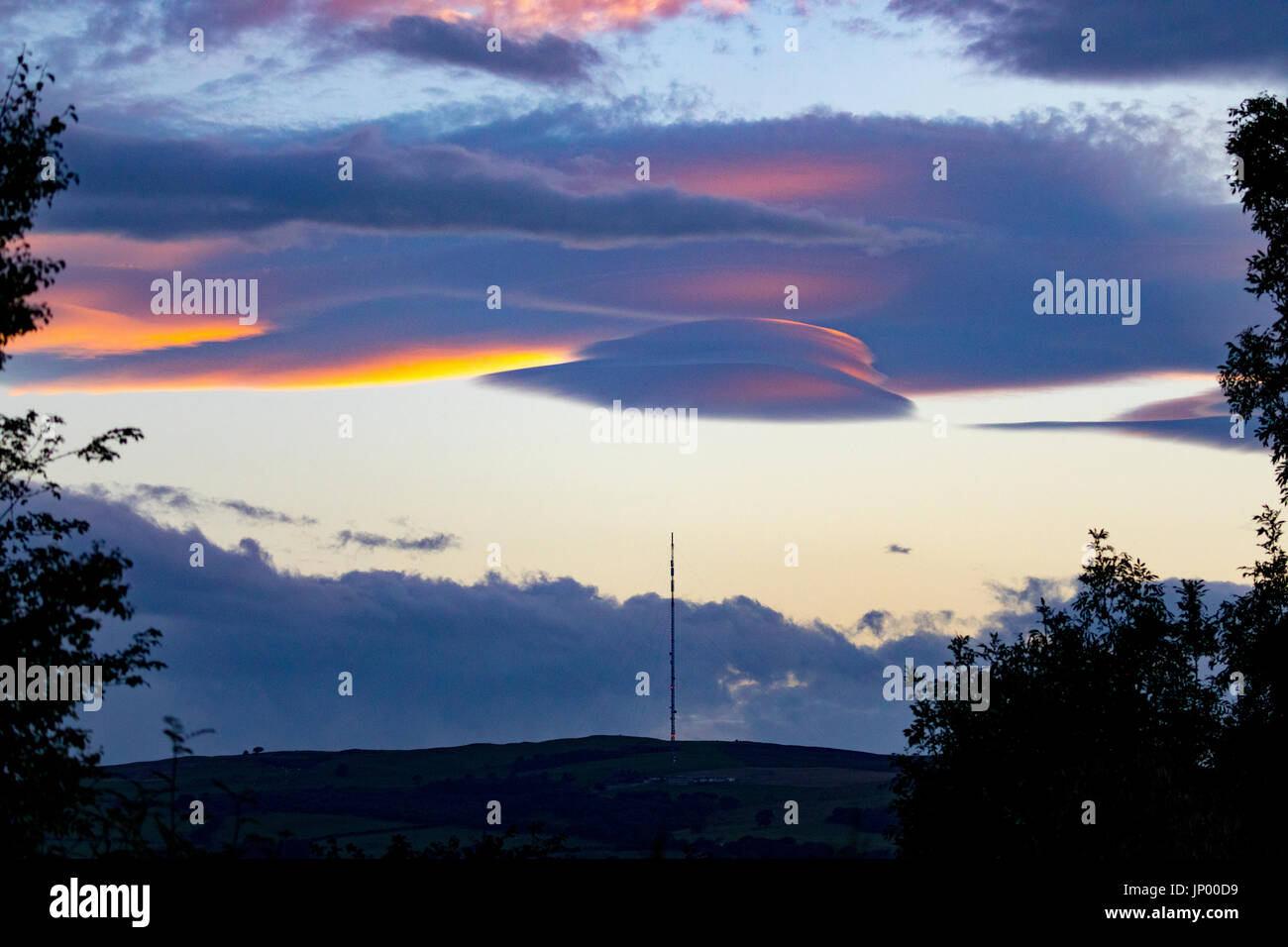 Seltsame Wolken bekannt als linsenförmige Wolken erscheinen über den Moel-y-Parc Mast auf den Hügeln Clwydian Range, Wales Stockfoto