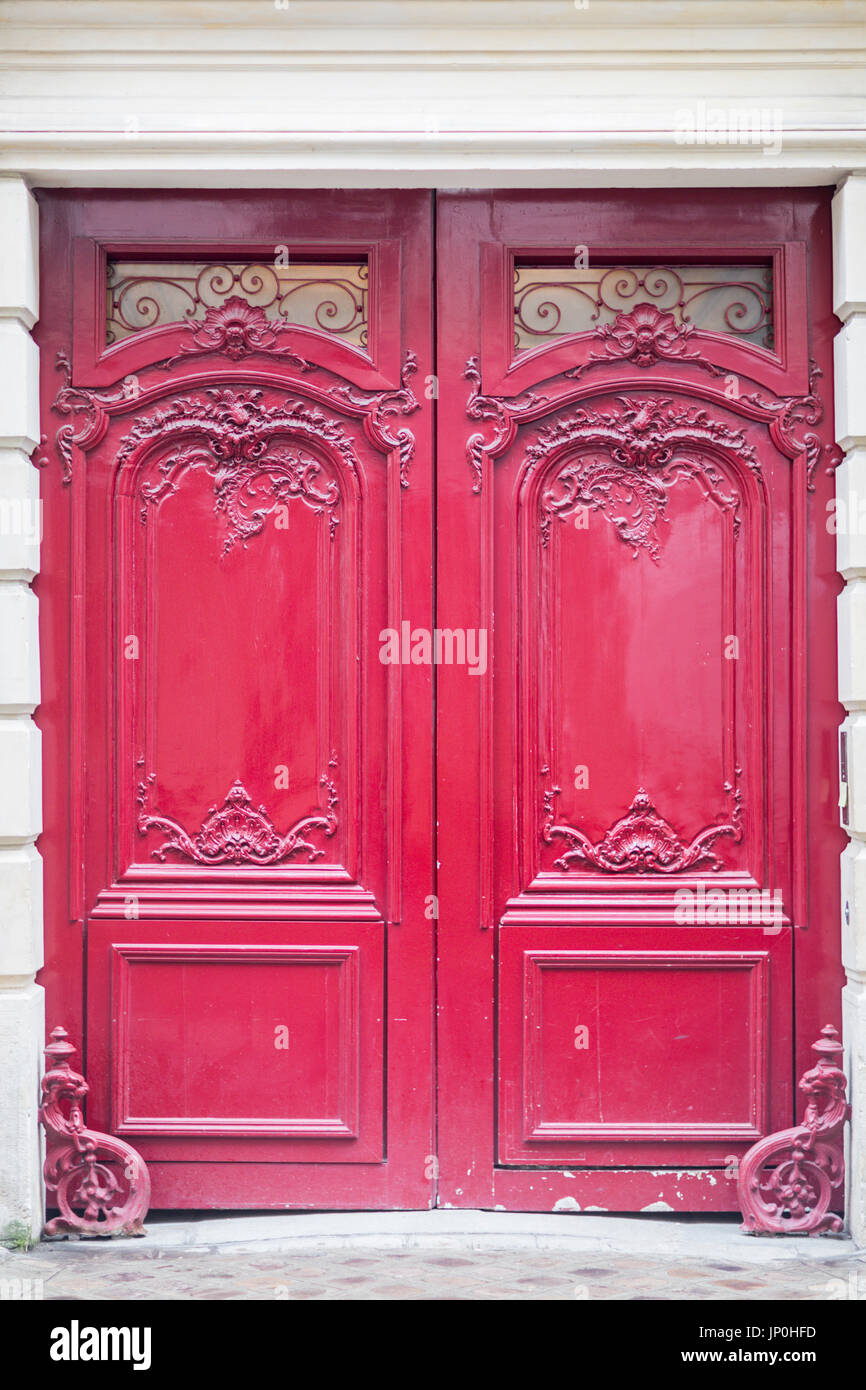 Paris, Frankreich - 2. März 2016: Rote Tür mit kunstvollen Schnitzereien und eleganten Bogen in Paris. Stockfoto