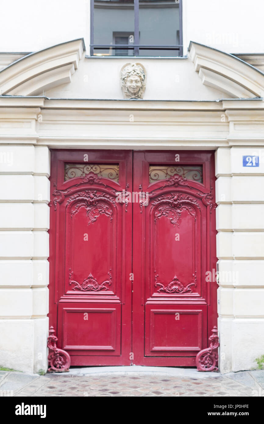 Paris, Frankreich - 2. März 2016: Rote Tür mit kunstvollen Schnitzereien und eleganten Bogen in Paris. Stockfoto