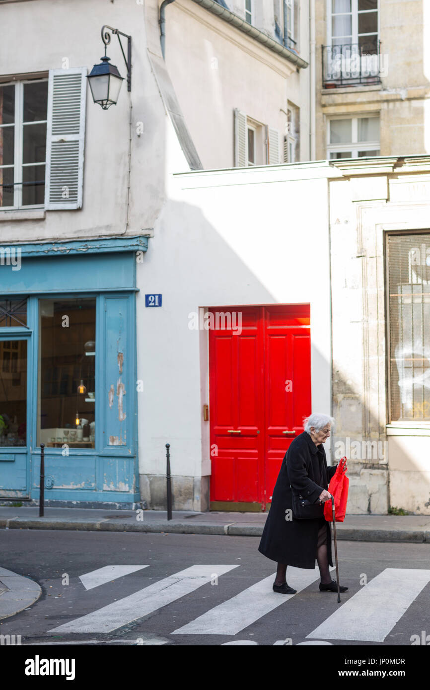 Paris, Frankreich - 2. März 2016: Ältere Dame geht vorbei an alten Gebäuden auf Rue du Petit Musc in Marais, Paris mit bunten Türen und Fenstern Stockfoto
