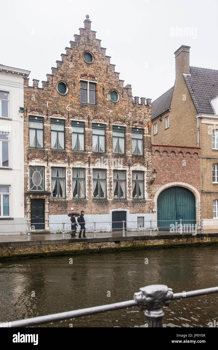 Brügge, Belgien – 31. Oktober 2010: Paar mit Regenschirm vor alten Zunfthaus über Kanal in Brügge, Belgien. Stockfoto