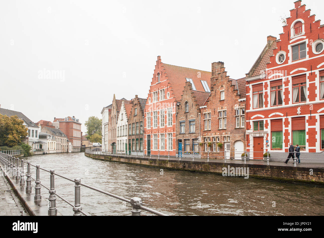 Brügge, Belgien – 31. Oktober 2010: Fußgänger gehen Teil Gildenhäuser durch einen Kanal in Brügge an einem regnerischen Herbsttag. Stockfoto