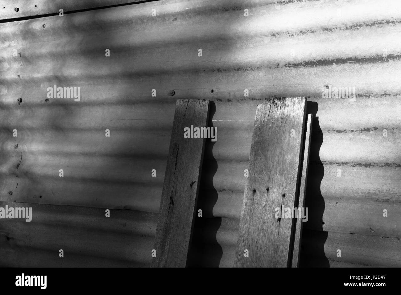 Stücke von Schnittholz, wahrscheinlich alte Dielenboden, lehnen an einer alten Wellblech Wand eines Garten auf einem Grundstück in Land NSW, Australien vergossen Stockfoto