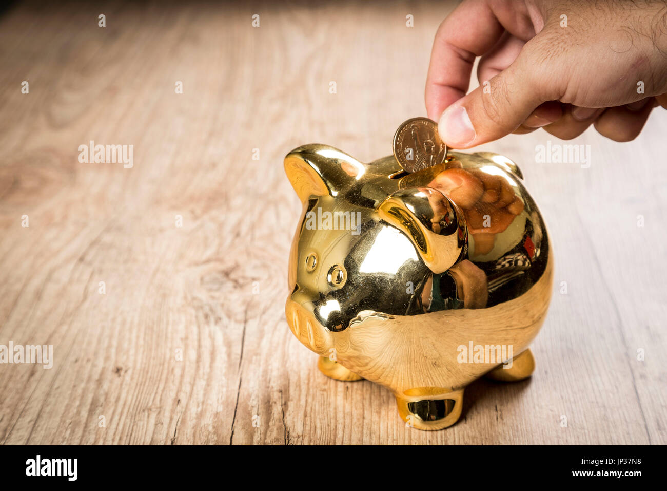 Setzen eine 1-Dollar-Münze in ein Sparschwein Stockfoto