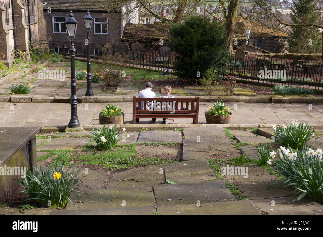 Paar sitzt auf der Bank im Kirchhof, Haworth, West Yorkshire Stockfoto