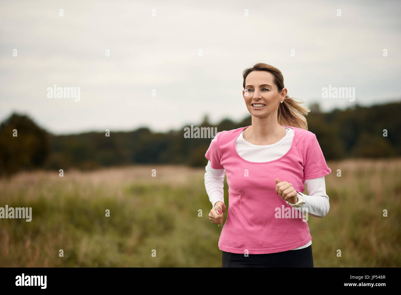 Stets gut gelaunte Frau läuft durch Feld im Herbst, Textfreiraum auf der linken Seite Stockfoto