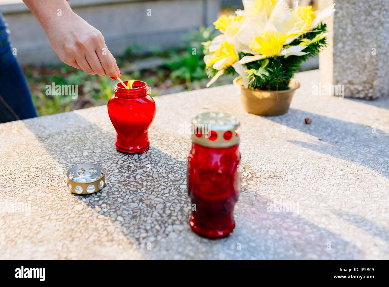 Eine Frau zündet eine Kerze am Grab. Vorbereitungen für Allerheiligen am 1. November Stockfoto