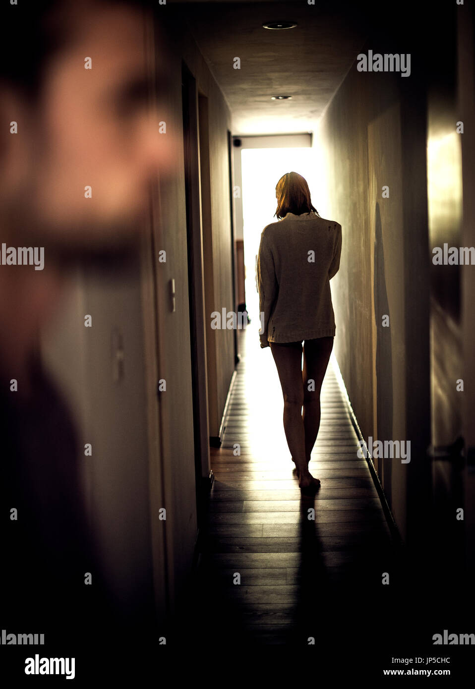 Eine Frau walkin einen Korridor von einem Mann im Vordergrund. Stockfoto