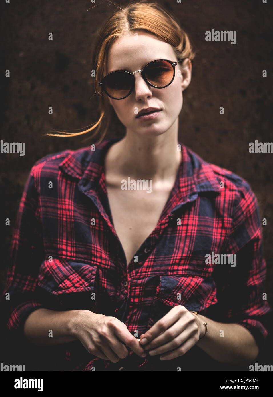 Eine Frau mit Sonnenbrille Stand gegen eine Wand und sah in Schuss. Stockfoto