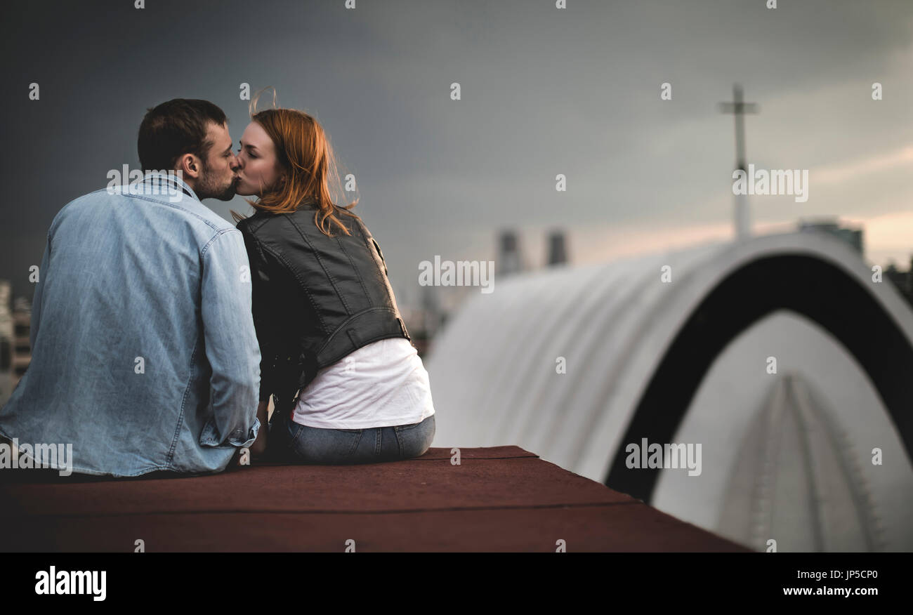 Ein paar sitzen und küssen auf den Dächern der Stadt. Stockfoto