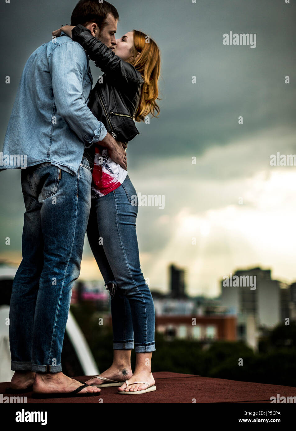 Ein paar stehen und küssen auf den Dächern der Stadt. Stockfoto