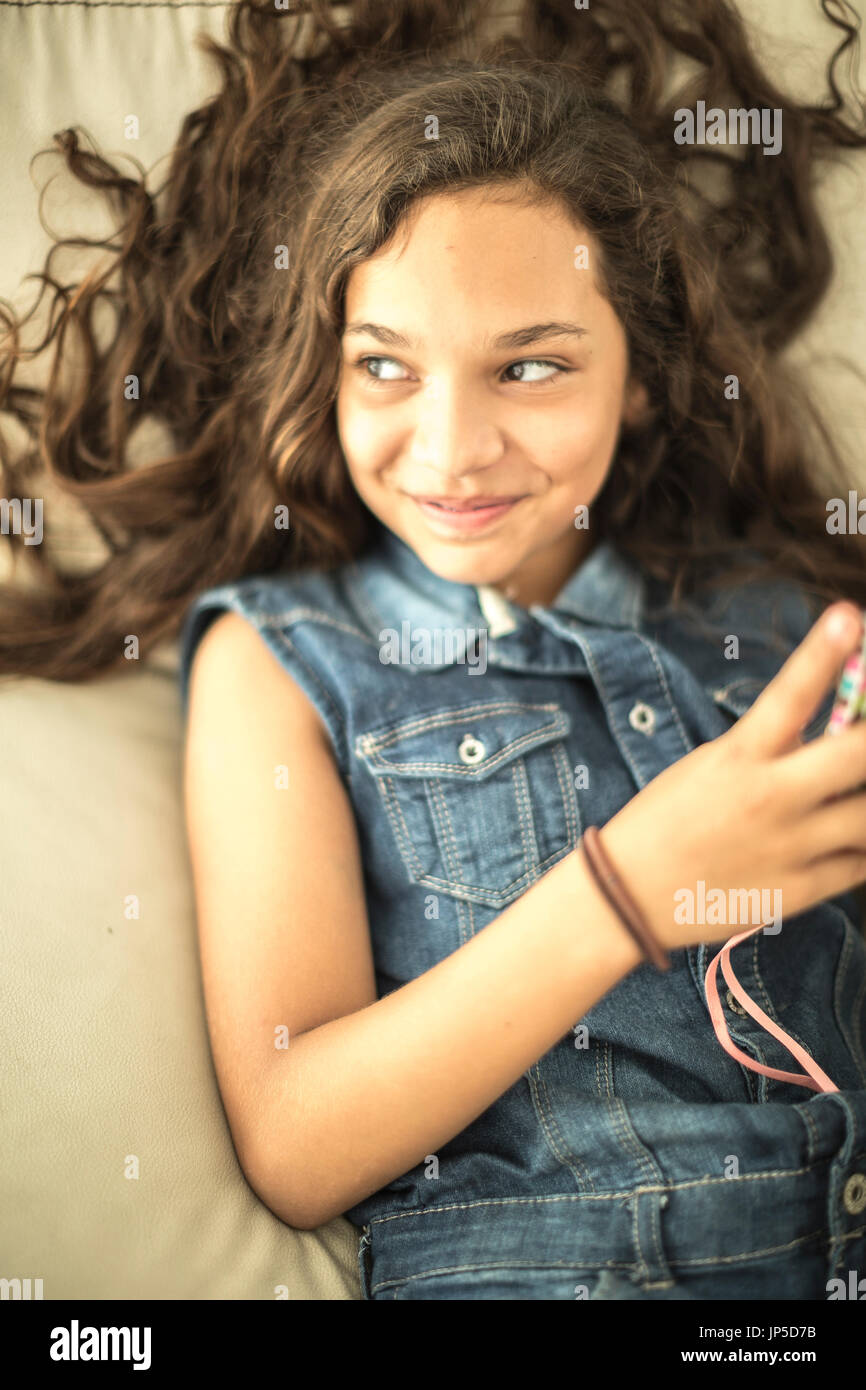 Ein Mädchen hinlegen, halten eines Handys und lächelnd. Stockfoto