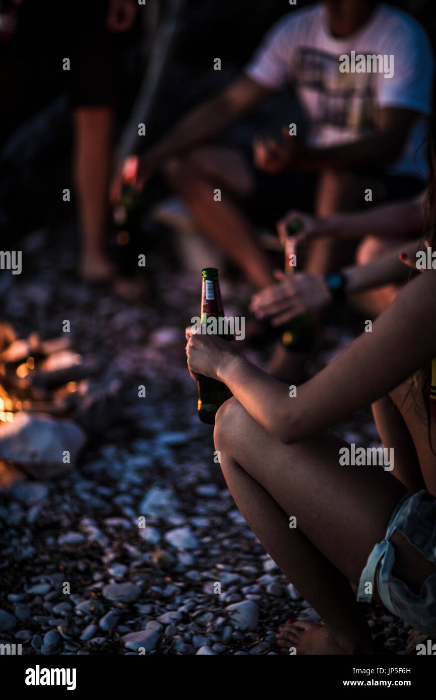 Eine Gruppe junger Menschen versammelten sich am Strand um ein Lagerfeuer. Stockfoto