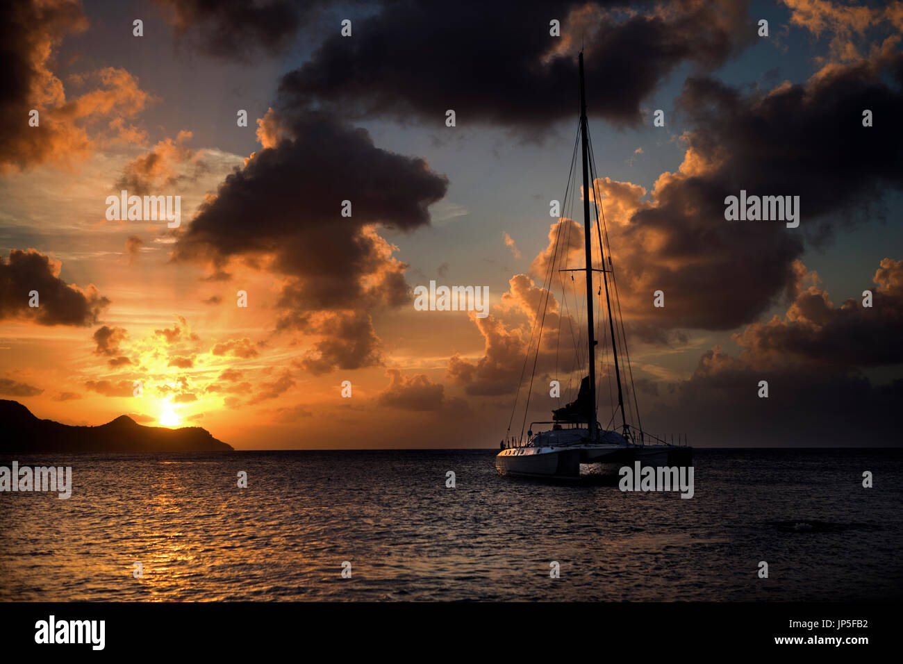 Kajütsegelboot auf dem Ozean bei bewölktem Himmel bei Sonnenuntergang. Stockfoto
