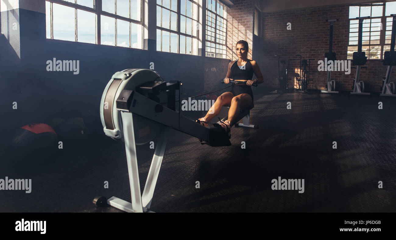 Sportliche junge Frau auf TrainergerГ im Fitnessstudio trainieren. Frau ihre Muskeln zu stärken, durch Ziehen an Gewicht in der Turnhalle. Stockfoto