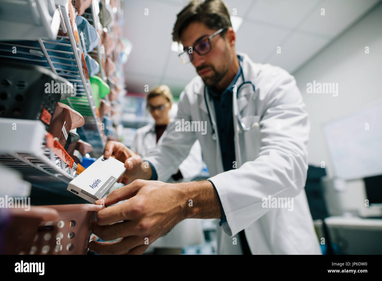 Apotheker, die auf der Suche nach einem Medikament auf Regal. Männlichen Apotheker Prüfung bestand in einem Regal. Medizinisches Personal im Krankenhausapotheke arbeiten. Stockfoto