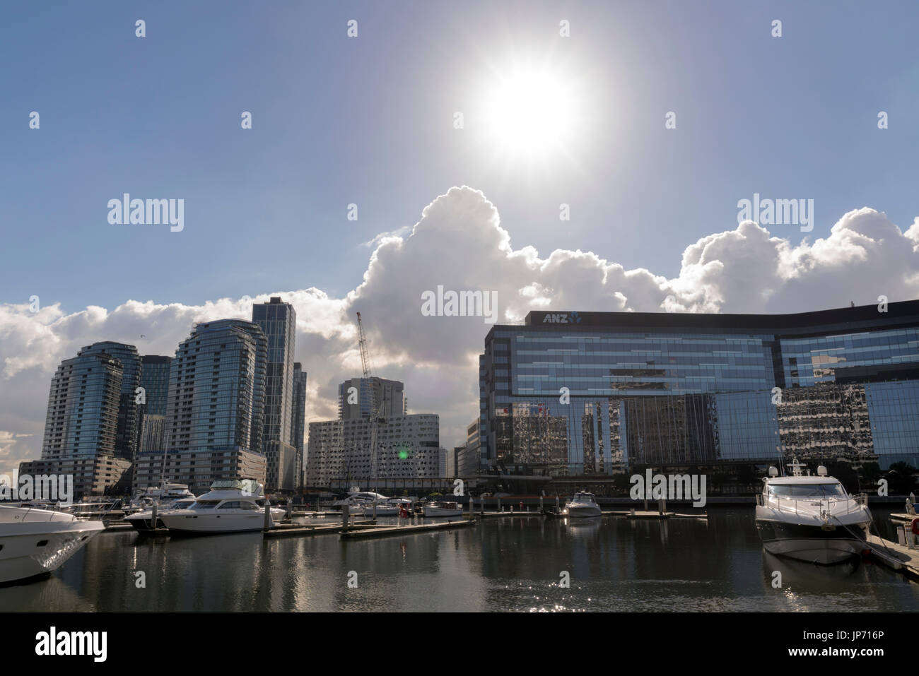 Riesige Sonne auf Docklands, Melbourne, Victoria, Australien. Gebäude am Wasser und Marina, Wasser und Glas Sekt in der Sonne. Stockfoto