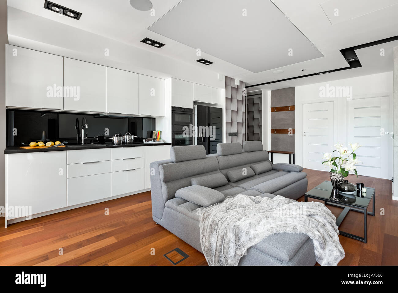 Offene Küche mit weißen Möbeln und extra großen grauen sofa Stockfoto