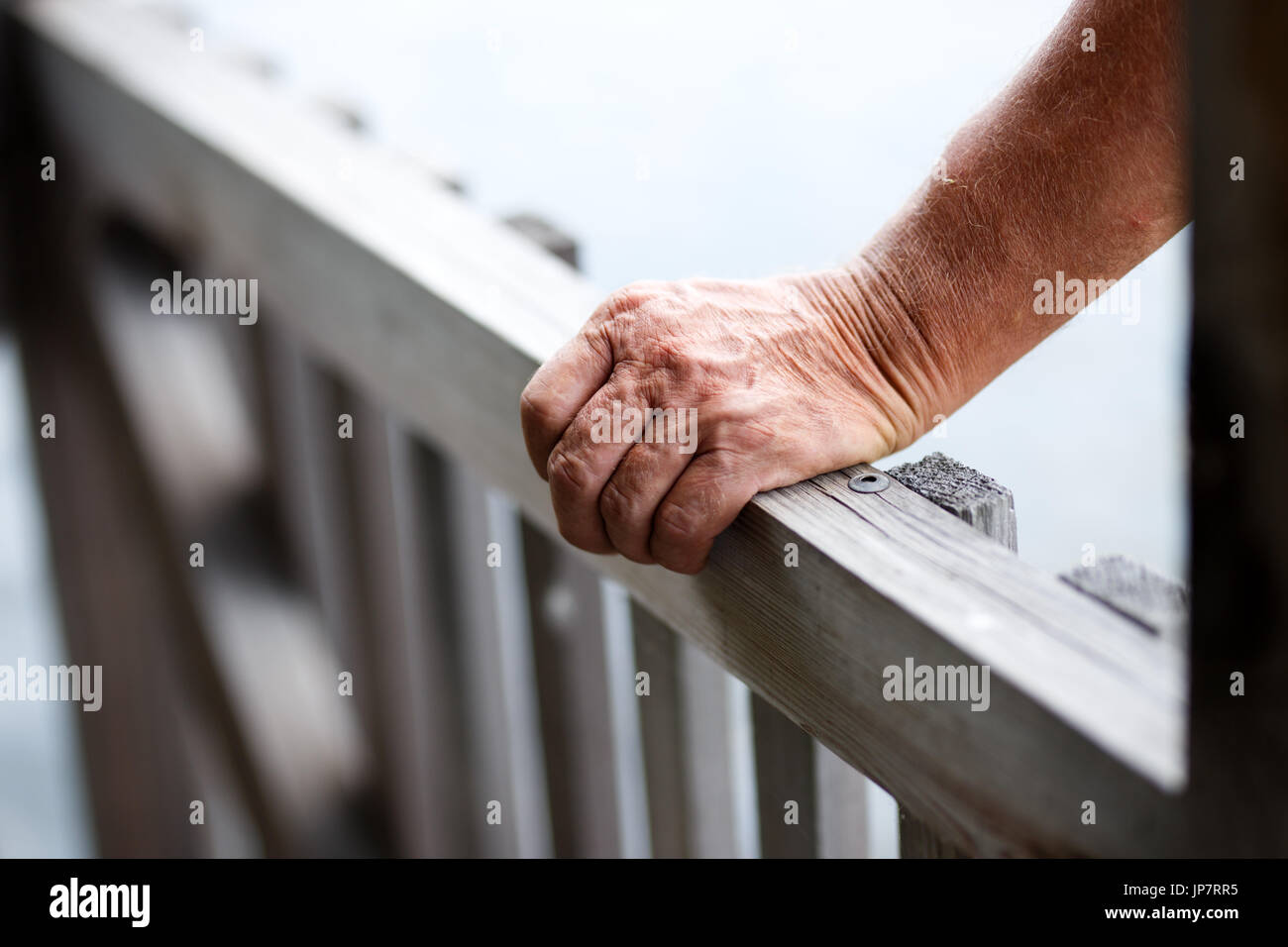 Nahaufnahme der alte Mann in der Nähe von Holzzaun beim Geländer Hand anziehen. Stockfoto