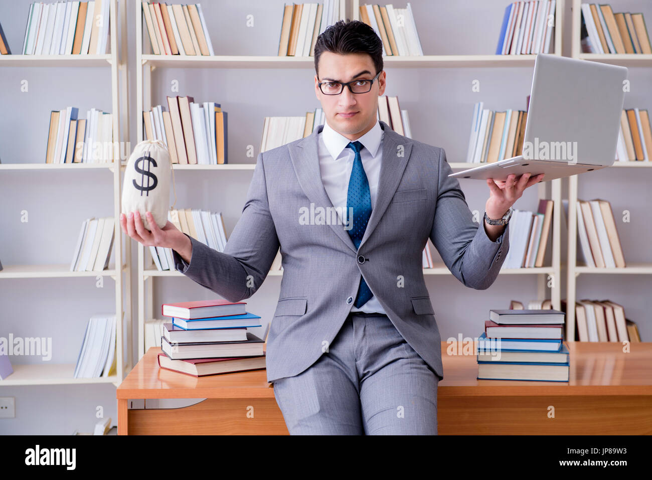 Geschäftsmann in Bibliothek mit meschotschek Geld und laptop Stockfoto
