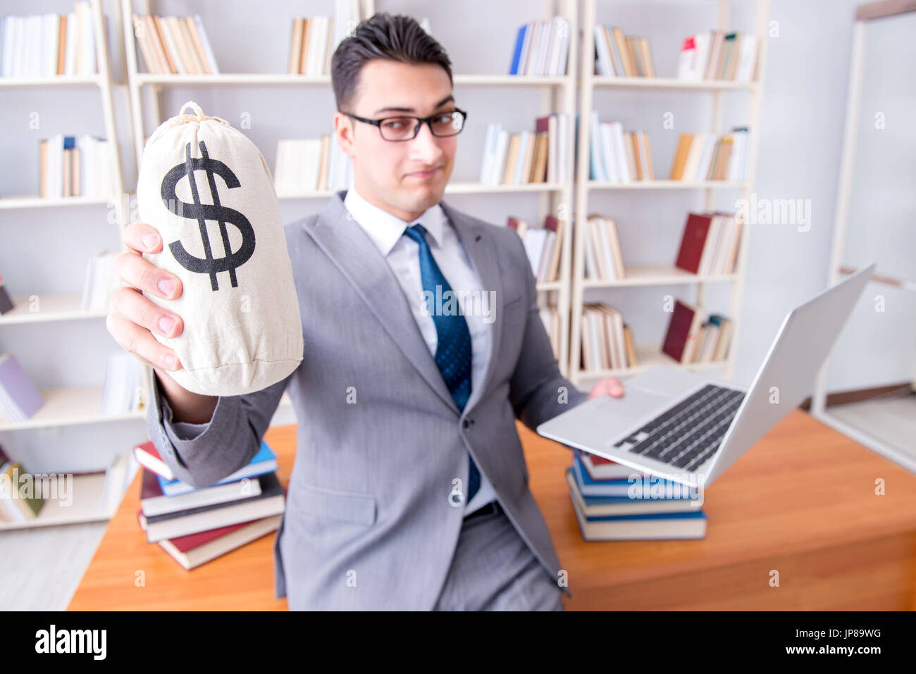 Geschäftsmann in Bibliothek mit meschotschek Geld und laptop Stockfoto