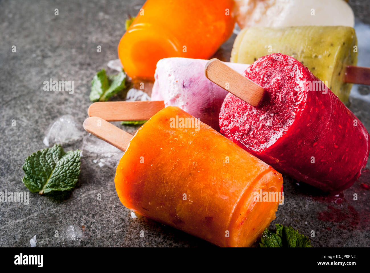 Gesunden Sommer Desserts. Eis Eis am Stiel. Gefrorene tropische Säfte, Smoothies Blaubeeren. Johannisbeere, Orange, Mango, Kiwi, Banane, Kokos, Himbeere Stockfoto