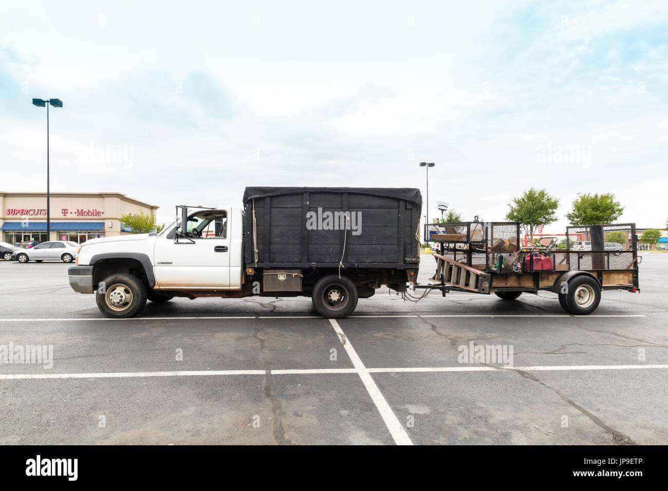 Ein Chevrolet Pickup mit Sideboards mit einem Dienstprogramm Anhänger voller Rasen Pflege Equipment parkte auf einem Parkplatz in Oklahoma City, Oklahoma, USA. Stockfoto