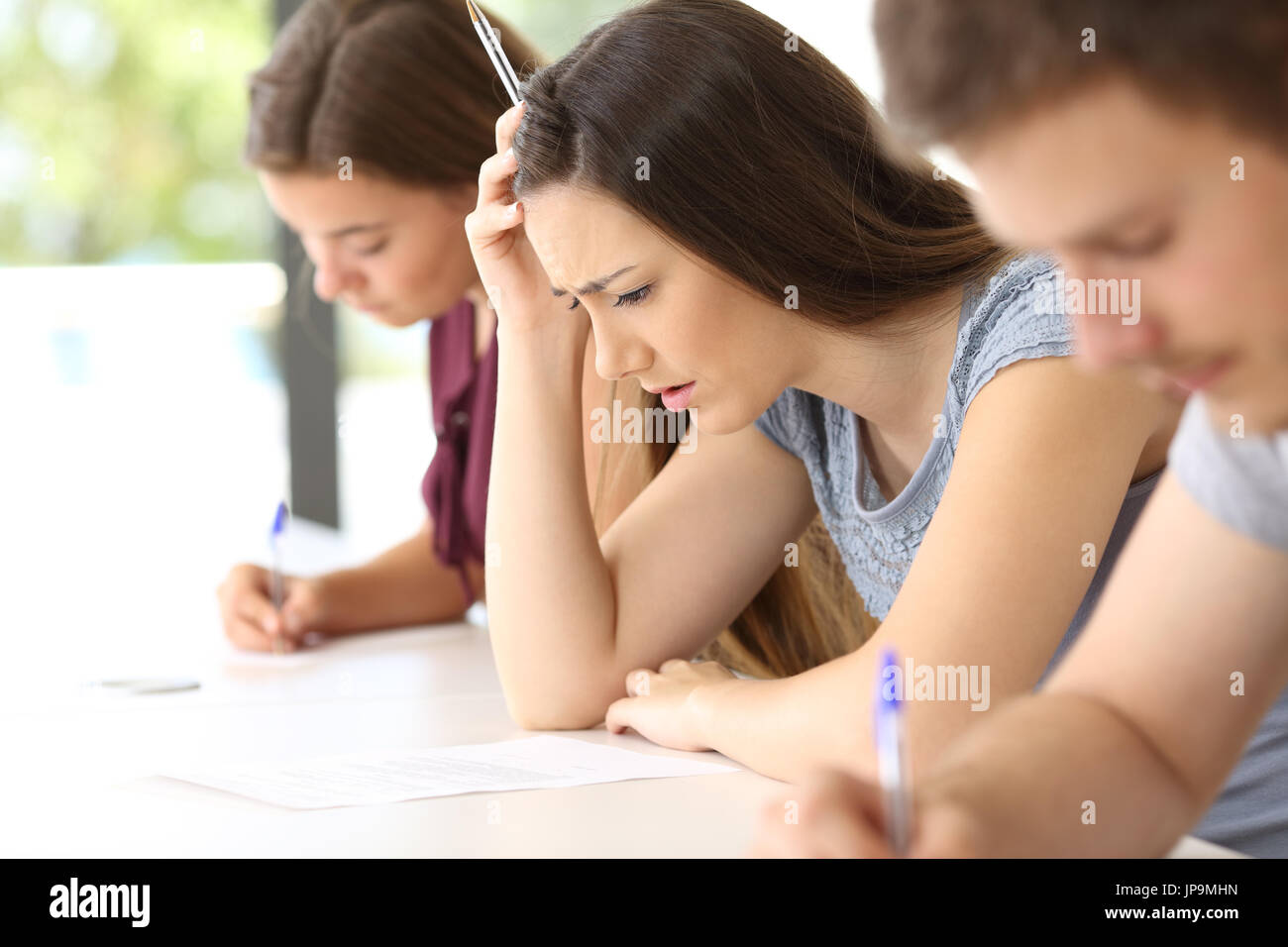 Seitenansicht eines besorgt Studenten versuchen, eine schwierige Prüfung in einem Klassenzimmer zu tun Stockfoto
