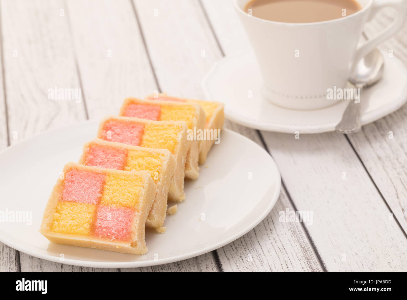 Scheiben von Battenburg Kuchen mit einer Tasse Kaffee Stockfoto