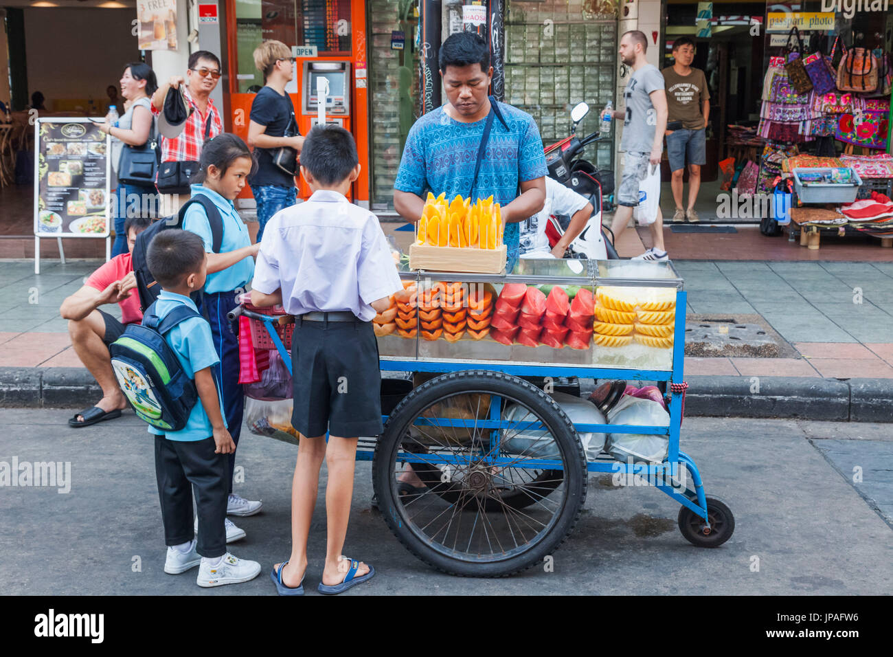 Thailand, Bangkok, Khaosan Road, Thai Schule Kinder kaufen frisches Obst aus Straßenhändler Stockfoto