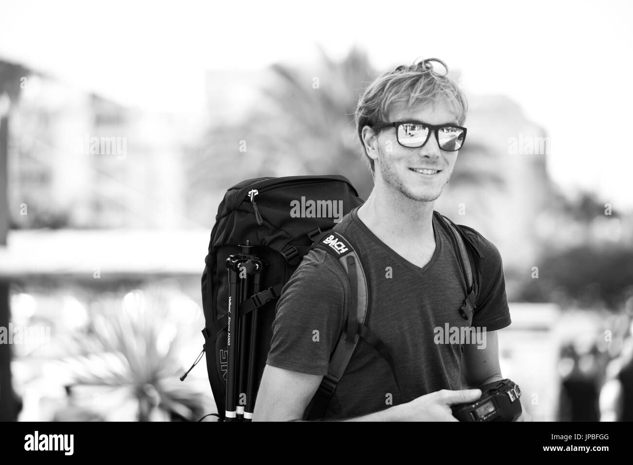 junger Mann steht mit Rucksack und Kamera auf der Kanarischen Insel und lächelt in die Kamera Stockfoto