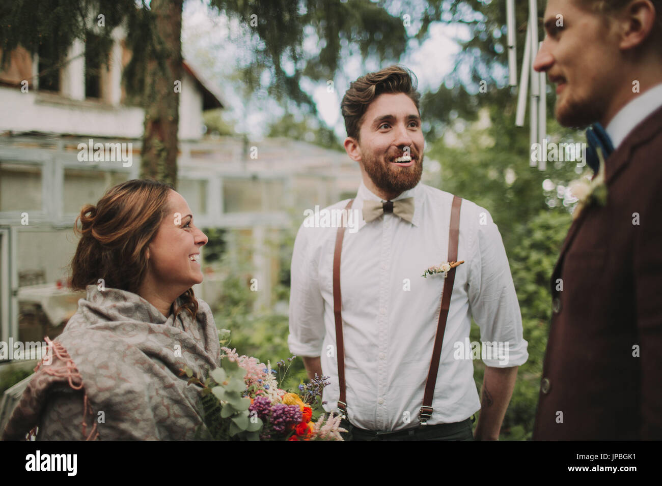 Alternative Hochzeit, Braut und Bräutigam im Gespräch mit einem Freund Stockfoto