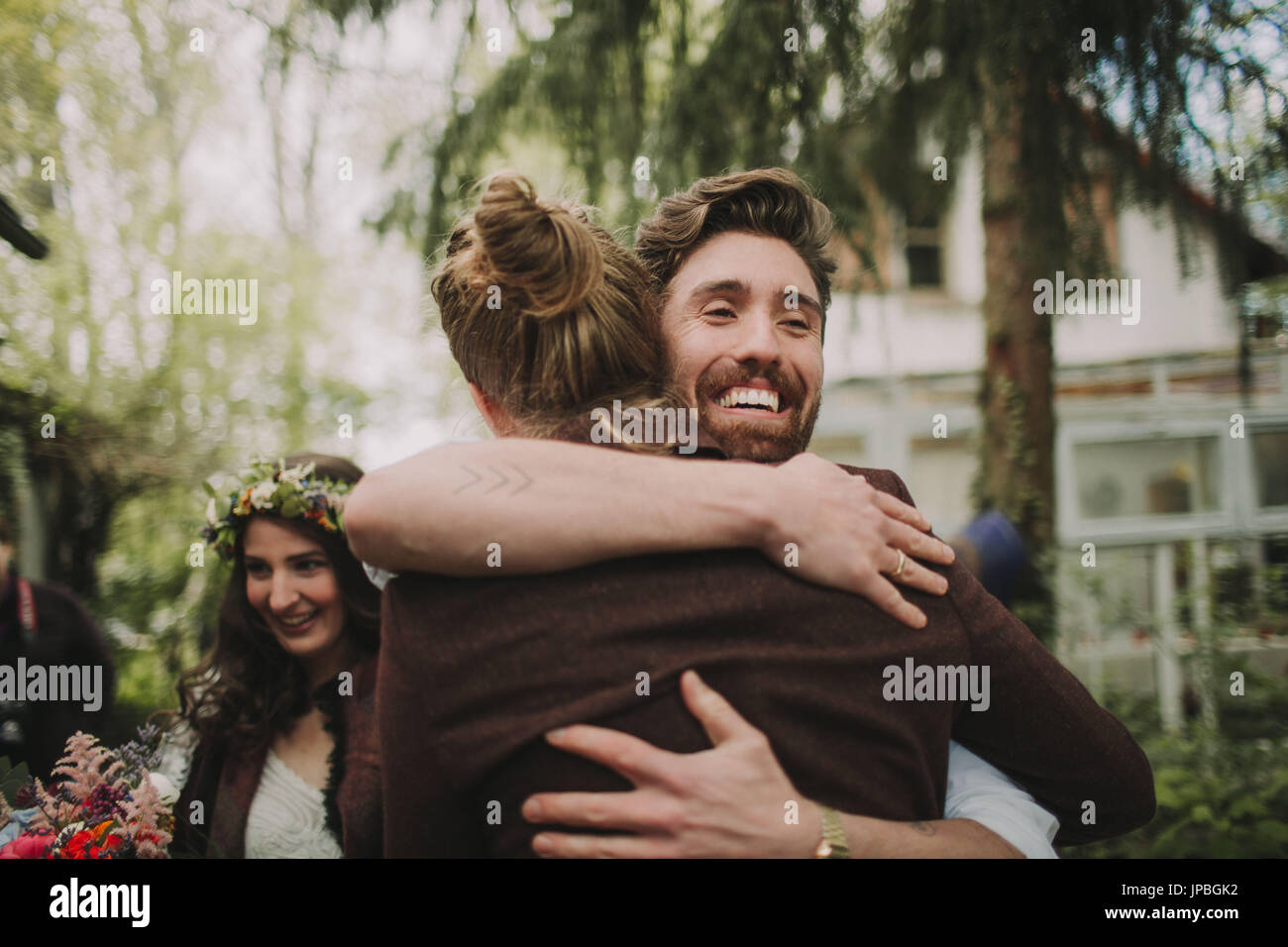 Alternative Hochzeit, Freund umarmt den Bräutigam Stockfoto