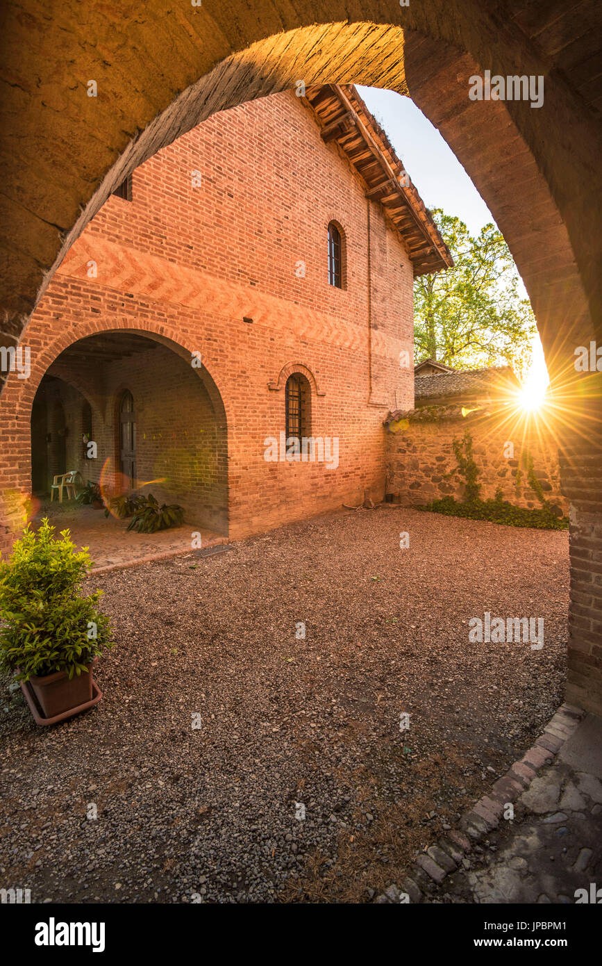 Grazzano Visconti, Vigolzone, Piacenza Bezirk, Emilia Romagna, Italien. Innenhof der Backsteinhäuser bei Sonnenuntergang. Stockfoto