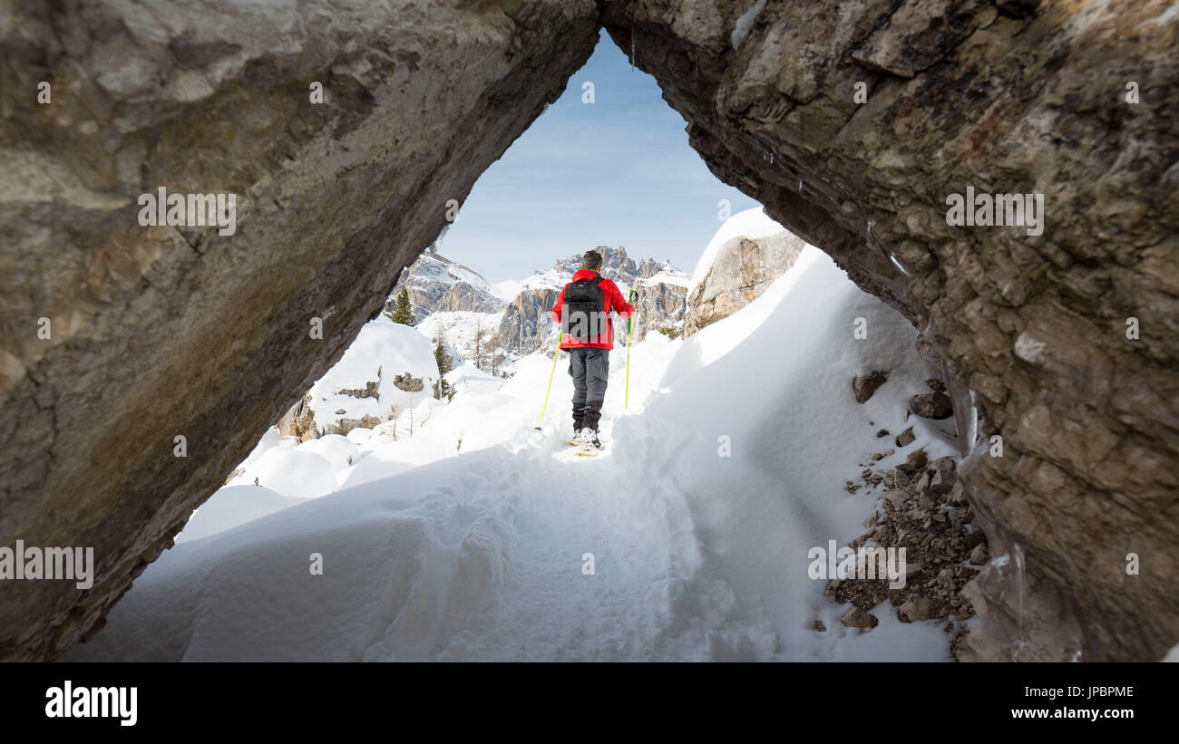 ein bezaubernder Blick ein Wanderer mit Schneeschuhen durch einen natürlichen Tunnel in den Felsen gesehen Provinz Belluno, Region Venetien, Italien, Europa, Stockfoto
