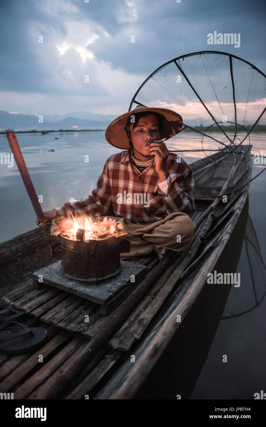 Inle-See, Nyaungshwe Township Taunggyi Bezirk, Myanmar (Burma). Lokale Fischer vor der Morgendämmerung mit Kamin auf dem Boot. Stockfoto