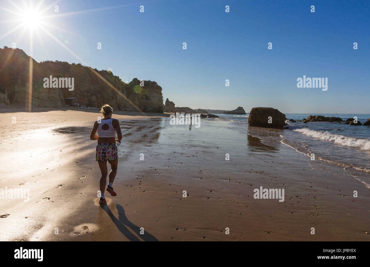 Sonnenstrahlen auf einen Läufer auf dem feinen Sandstrand gebadet durch den Ozean Praia da Rocha Portimao Faro Bezirk Algarve Portugal Europa Stockfoto