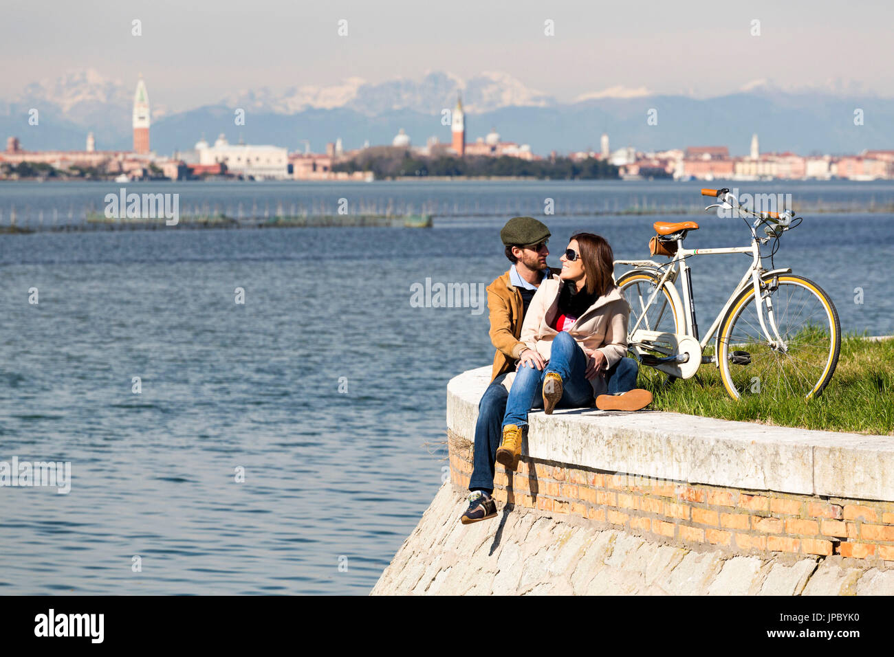 Ein paar entspannende an der Waterfront in Lido. Auf der Rückseite geschliffen, Venedig und den Dolomiten. Venedig, Veneto, Italien. Stockfoto
