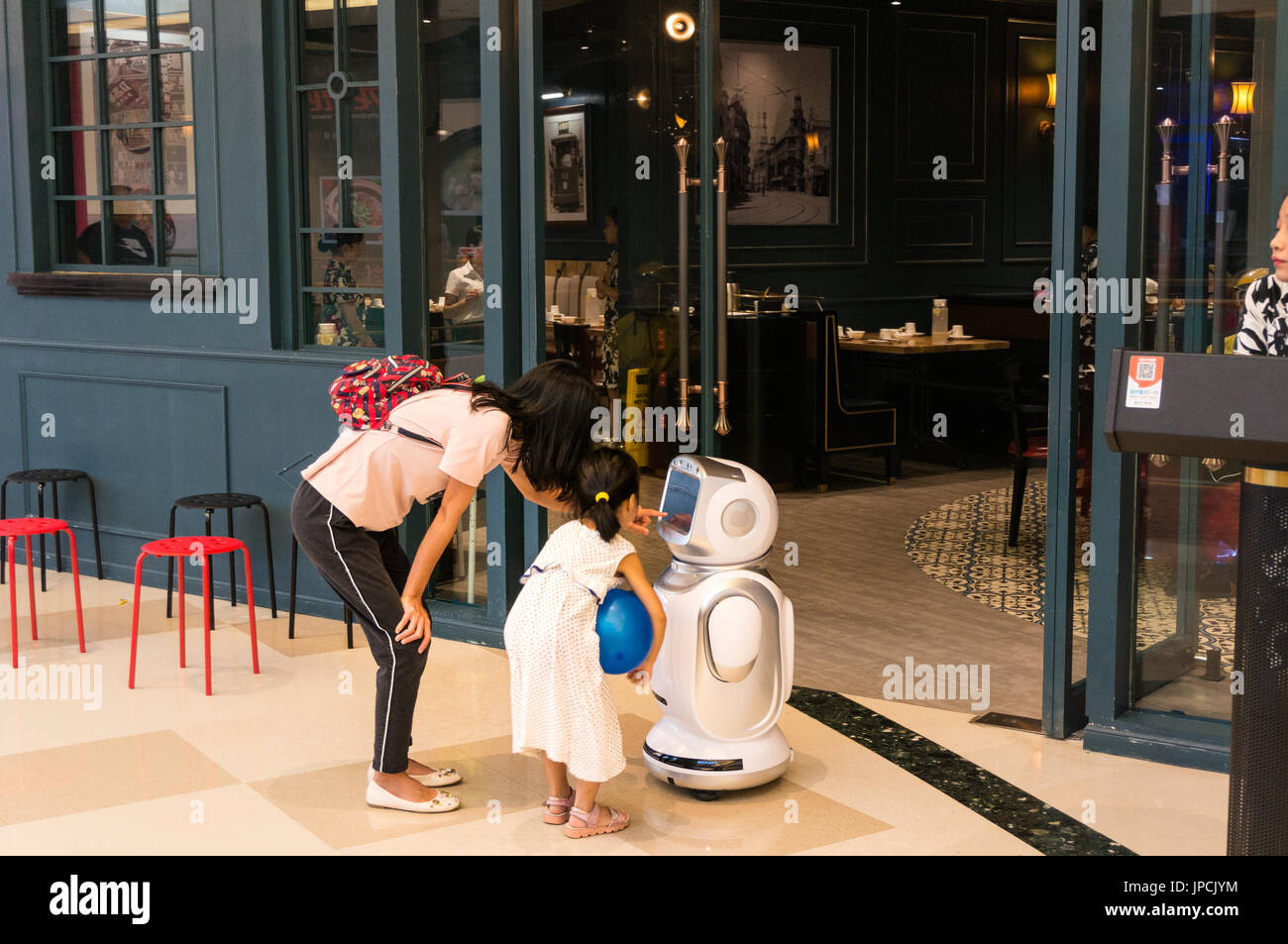 Mutter und junge Mädchen, die Interaktion mit Restaurant Roboter in Shenzhen, China Stockfoto