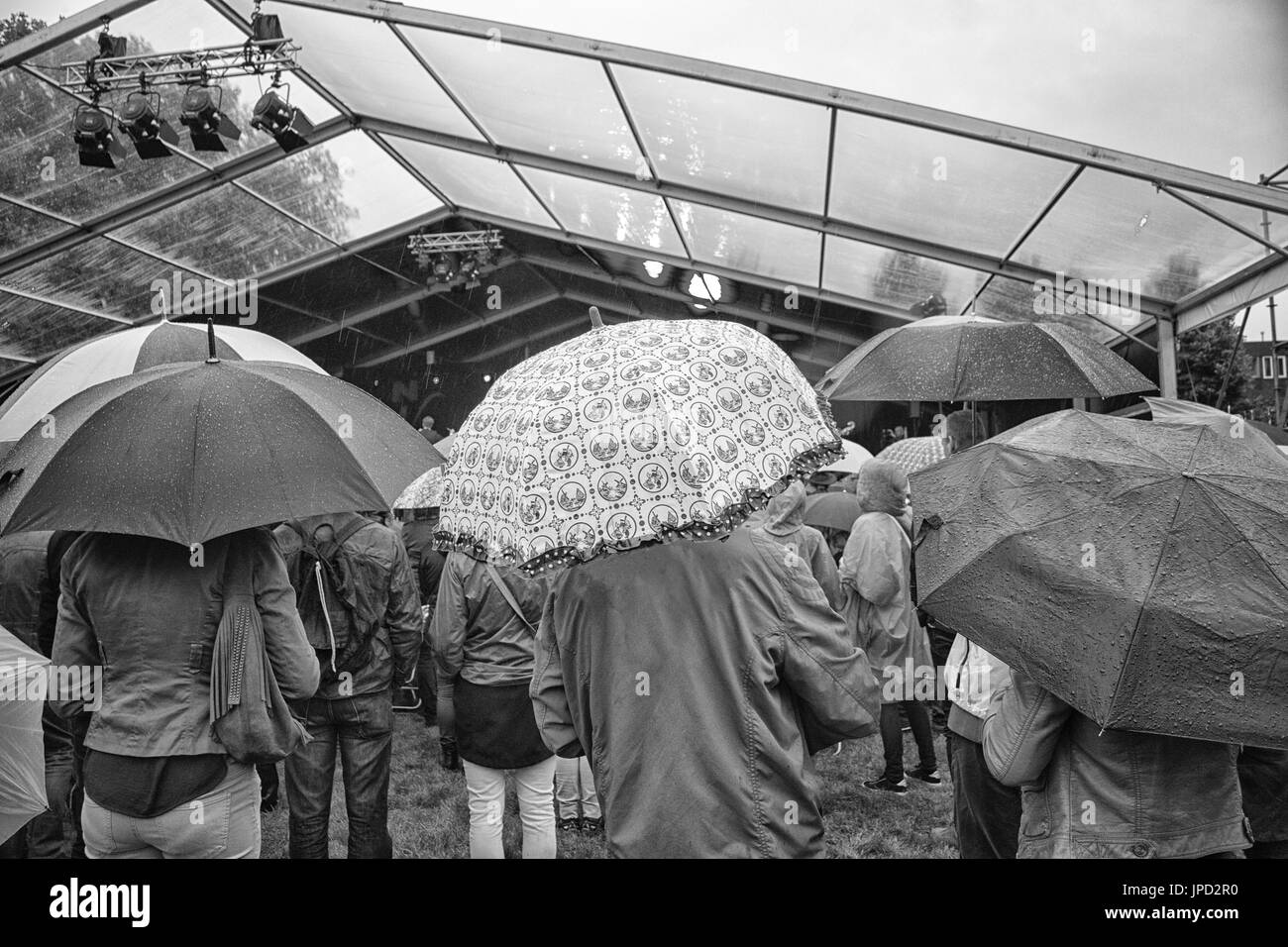 Gruppe von Menschen mit Regenschirmen im Regen während eines Festivals Stockfoto