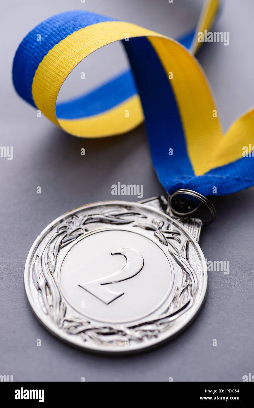 Close-up Studioaufnahme des zweiten Platz Silber Medaille mit gestreiften blauen und gelben Band auf grauem Hintergrund Stockfoto