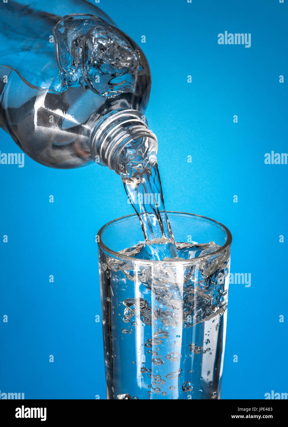 Wasser in Glas gießen, über blauem Hintergrund Stockfoto