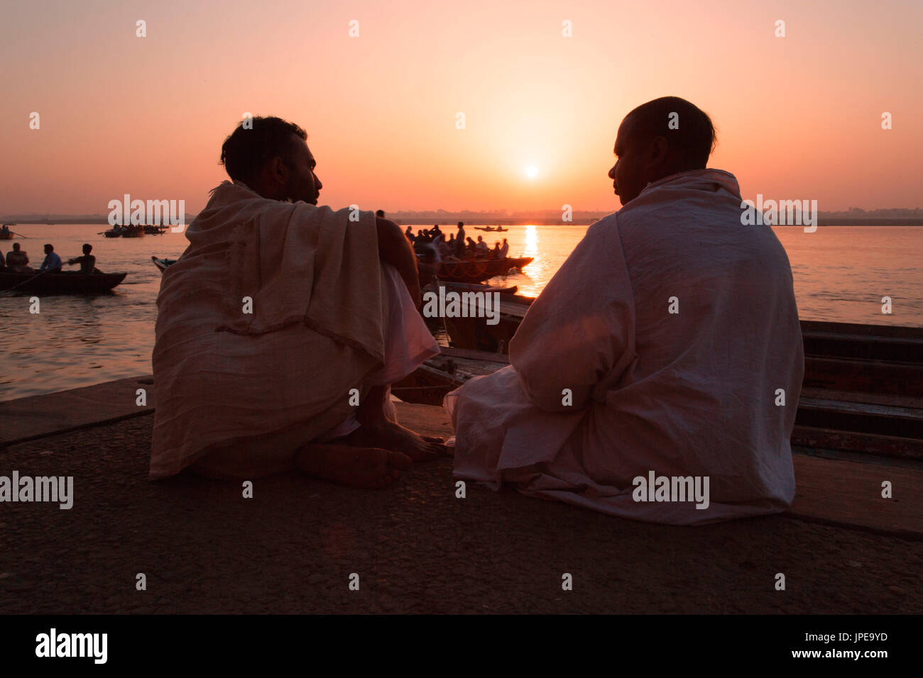 Asien, Indien, Varanasi Bezirk. Jungen sitzen um den Sonnenaufgang am Ufer des Ganges Stockfoto