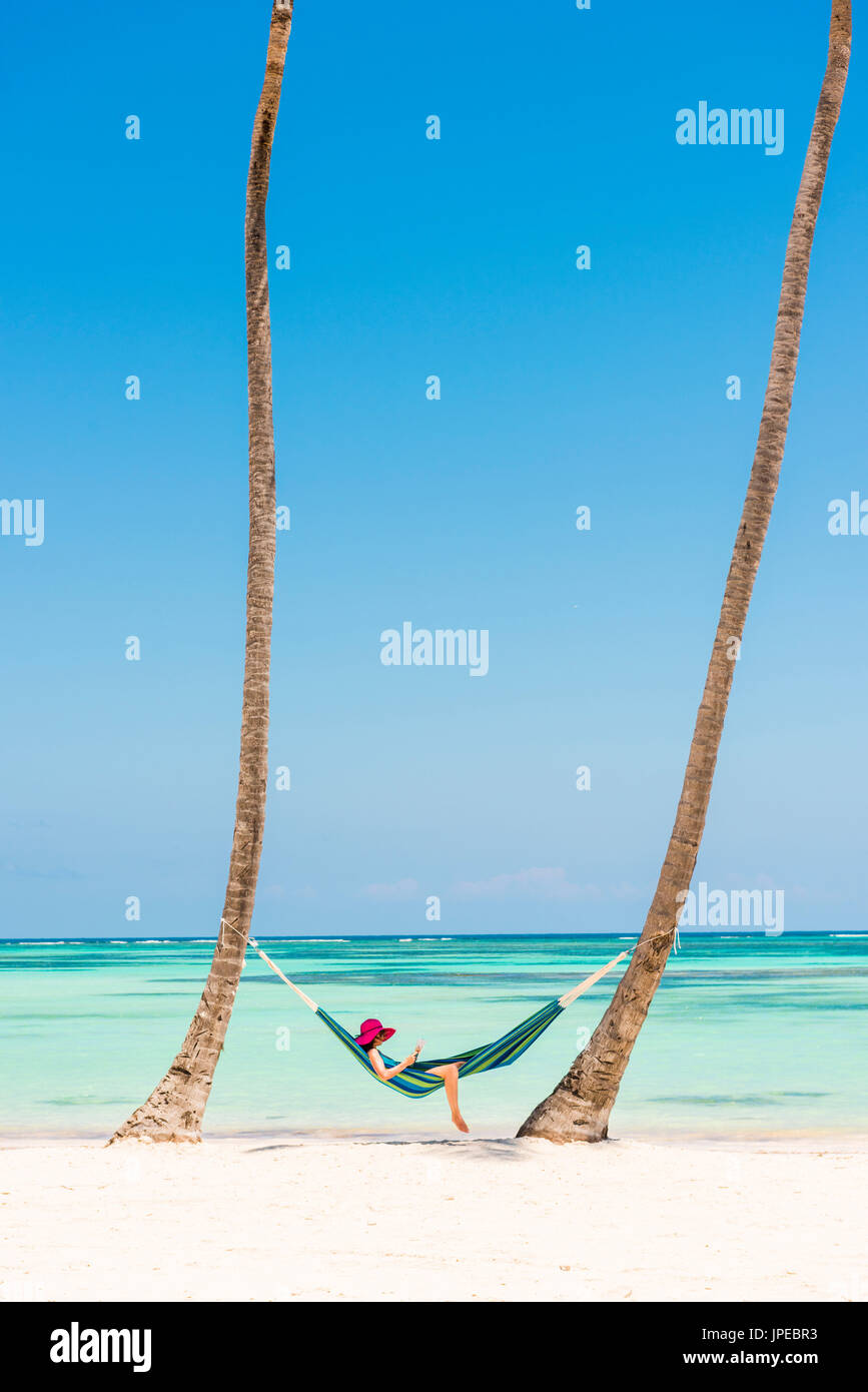 Juanillo Strand (Playa Juanillo), Punta Cana, Dominikanische Republik. Entspannen Sie sich auf einer Hängematte an einem palmengesäumten Strand (MR) Frau. Stockfoto