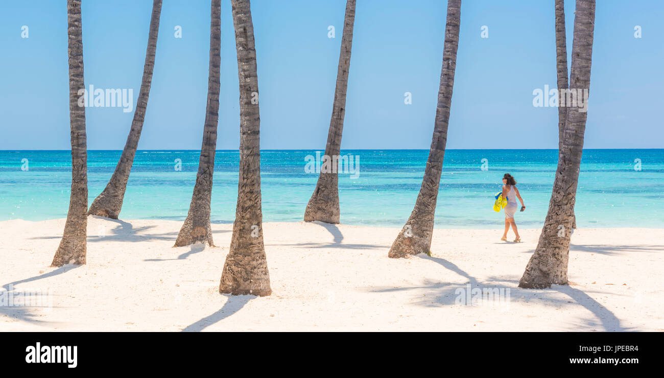 Juanillo Beach (playa Juanillo), Punta Cana, Dominikanische Republik. Frau zu Fuß auf den palmengesäumten Strand (MR). Stockfoto