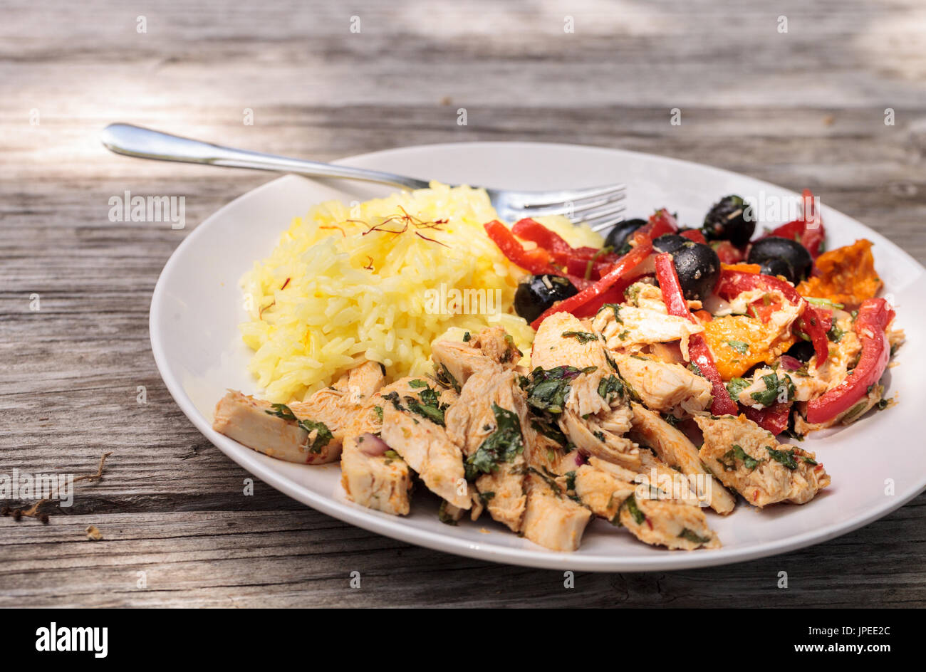 Spicy Chicken Diablo mit Koriander, Oliven, Paprika, Knoblauch und Zwiebeln auf gelber Safranreis serviert. Stockfoto